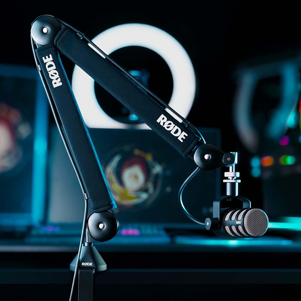 黒いPSA1+アームを机の端に固定し、別売PodMicを吊り下げた公式写真
