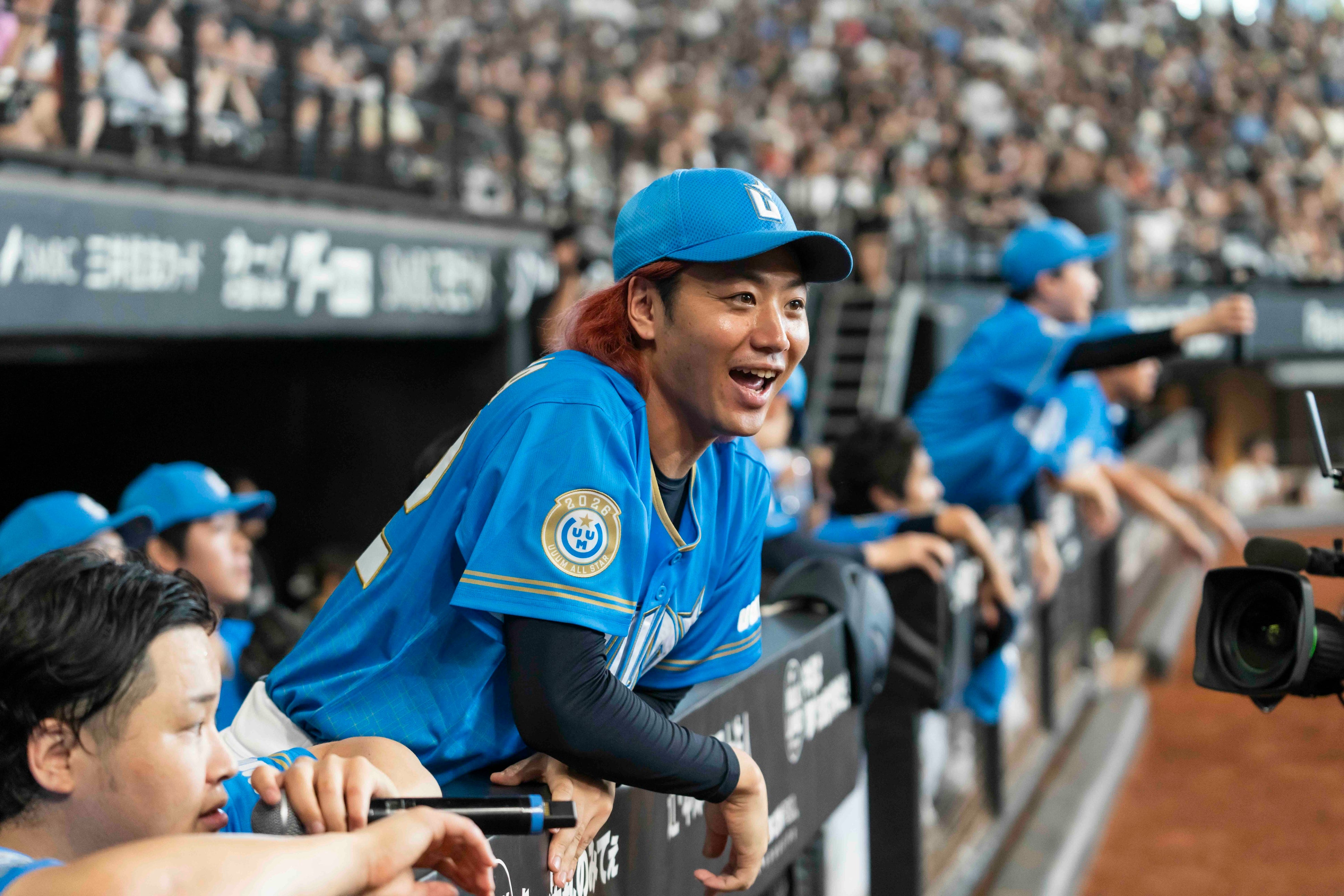 UUUM DAYの試合中、UUUMオールスターのメンバーがベンチからグラウンドを見る様子。